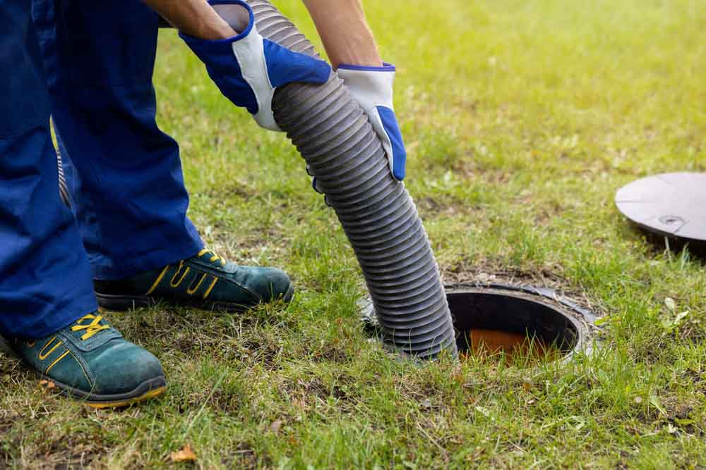 technician holding suction hose, performing septic pumping Lansing, MI